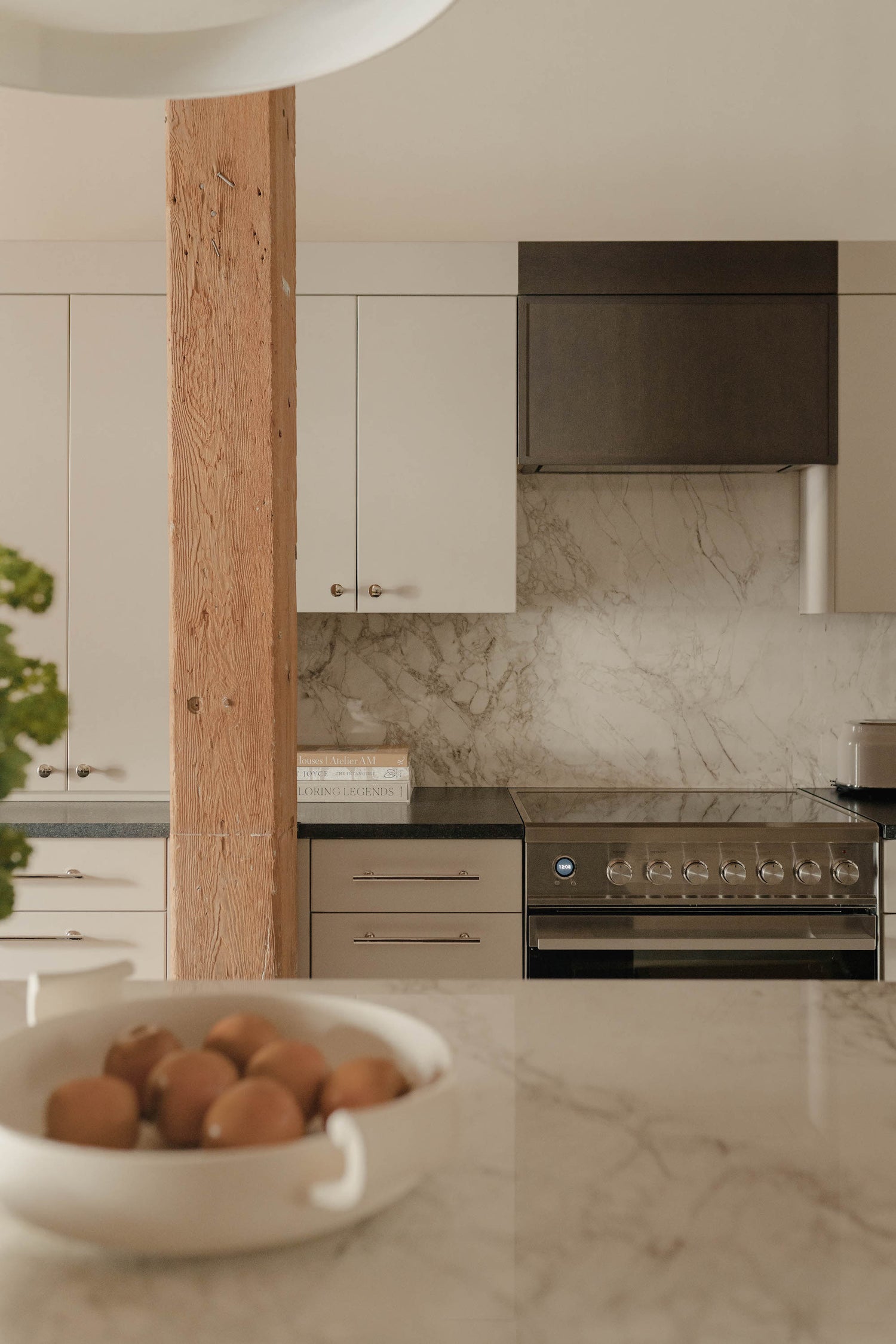 An urban kitchen turned warm and layered with a marble backsplash and upholstered stools, by Stephenson House.